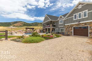 View of front of property with a garage, a balcony, a hot tub, a pergola, and a mountain view