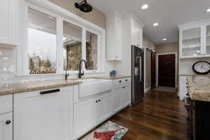 Kitchen with dark wood-type flooring, high end fridge, sink, a barn door, and white cabinets
