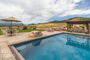 View of pool with a patio, a mountain view, and a pergola