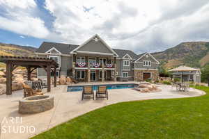 View of swimming pool featuring a patio, a lawn, an outdoor fire pit, a pergola, and a mountain view