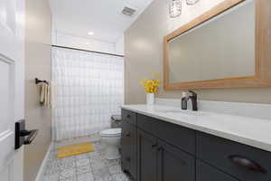 Full bathroom with shower / tub combo with curtain, vanity, toilet, and tile patterned flooring
