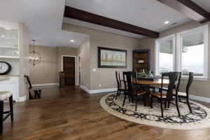 Dining area featuring beamed ceiling, dark hardwood / wood-style flooring, and an inviting chandelier