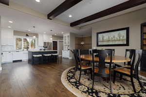 Dining room featuring beamed ceiling, dark hardwood / wood-style floors, and a chandelier