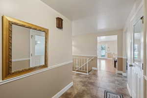 Hall with baseboards, tile patterned floors, and an upstairs landing