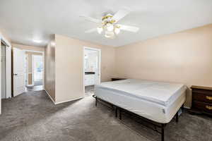Carpeted bedroom featuring baseboards, a ceiling fan, and ensuite bathroom