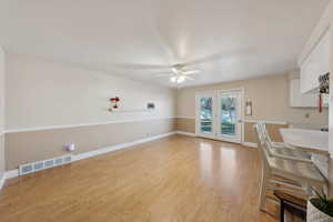 Unfurnished dining area with ceiling fan, french doors, light wood-style flooring, baseboards, and visible vents