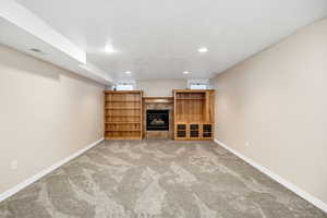 Finished below grade area with carpet floors, visible vents, baseboards, recessed lighting, and a textured ceiling
