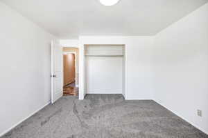 Unfurnished bedroom featuring carpet floors, baseboards, and a closet