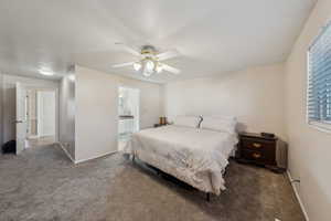 Carpeted bedroom with connected bathroom, a ceiling fan, and baseboards