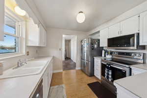 Kitchen with a sink, light countertops, white cabinets, and stainless steel appliances