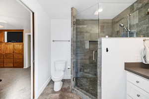 Bathroom with vanity, baseboards, a shower stall, and toilet