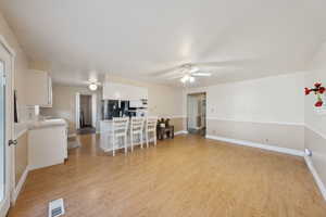 Living area featuring baseboards, ceiling fan, light wood-type flooring, and visible vents