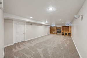 Finished basement featuring baseboards, recessed lighting, a textured ceiling, and light colored carpet