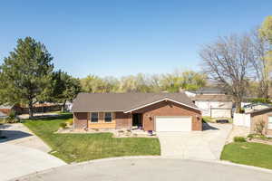 Ranch-style house featuring fence, an attached garage, a front lawn, brick siding, and driveway