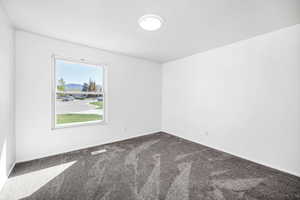 Unfurnished room featuring visible vents, baseboards, and dark colored carpet