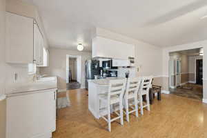 Kitchen with light wood-type flooring, a sink, white cabinets, and stainless steel appliances