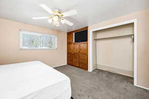Bedroom featuring baseboards, ceiling fan, a closet, and dark carpet