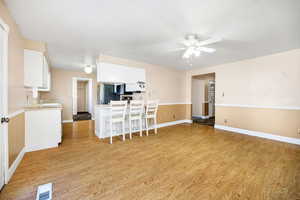 Living area featuring baseboards, ceiling fan, light wood-style flooring, and visible vents