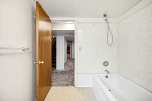 Bathroom with a textured ceiling, tile patterned floors, and shower / bathing tub combination