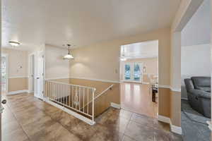 Corridor featuring baseboards, tile patterned flooring, and an upstairs landing