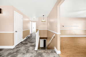 Hall with baseboards, an upstairs landing, and visible vents