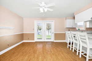 Unfurnished dining area featuring baseboards, light wood finished floors, ceiling fan, and visible vents