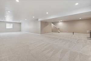 Basement featuring stairs, recessed lighting, baseboards, and light carpet