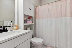 Full bathroom featuring toilet, curtained shower, and vanity