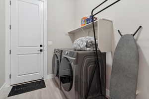 Laundry area with baseboards, separate washer and dryer, light wood finished floors, and laundry area