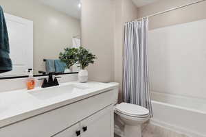 Bathroom with vanity, shower / bathtub combination with curtain, wood finished floors, and toilet