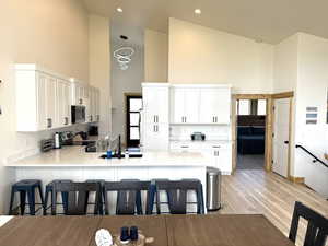 Kitchen with high vaulted ceiling, a peninsula, a kitchen breakfast bar, appliances with stainless steel appliances and quartz counter tops
