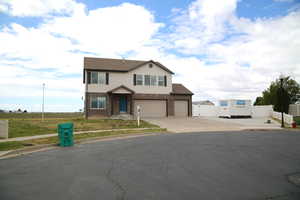 View of front of property featuring driveway, fence, brick siding, and an attached garage