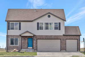View of front of property with roof with shingles, concrete driveway, a garage, and brick siding