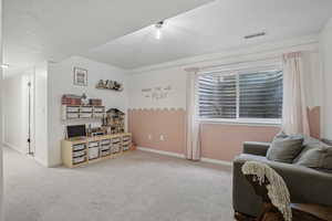 Sitting room with carpet flooring, baseboards, and a textured ceiling