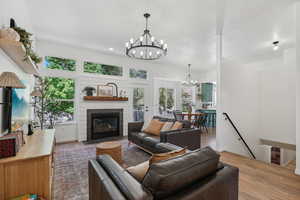 Living room with a chandelier, wood finished floors, a fireplace with flush hearth, and plenty of natural light