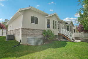 Back of property with stucco siding, cooling unit, and brick siding