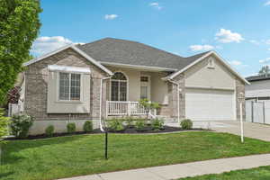 Single story home with covered porch, stucco siding, a garage, concrete driveway, and a front yard