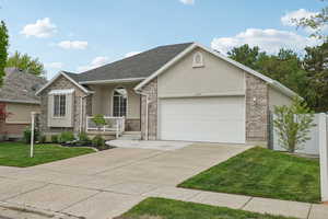 View of front of house featuring stucco siding, a porch, a garage, driveway, and a front yard