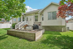 Rear view of property featuring a vegetable garden, stucco siding, and central AC
