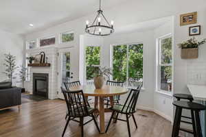 Dining room with plenty of natural light, light wood-style flooring, a chandelier, a fireplace with flush hearth, and recessed lighting