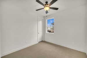 Unfurnished room with a ceiling fan, baseboards, and light carpet