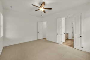 Unfurnished bedroom featuring light colored carpet, a ceiling fan, baseboards, and visible vents