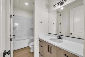 Full bathroom with visible vents, wood finished floors, vanity, toilet, and washtub / shower combination