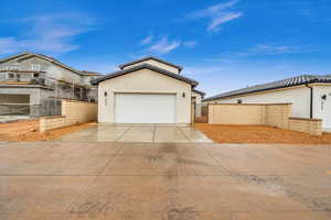 View of front of property featuring a gate, a garage, fence, concrete driveway, and stucco siding