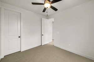 Unfurnished bedroom with baseboards, a ceiling fan, and light colored carpet