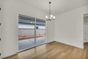 Unfurnished room with light wood-type flooring, baseboards, and a notable chandelier