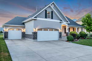 Craftsman-style house with covered porch, driveway, stone siding, and stucco siding