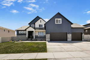 View of front of home featuring board and batten siding, fence, concrete driveway, and a front yard