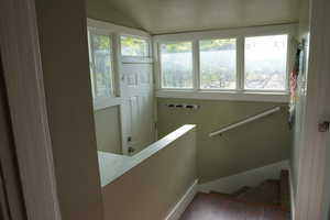 Staircase with a healthy amount of sunlight, baseboards, vaulted ceiling, and hardwood / wood-style floors