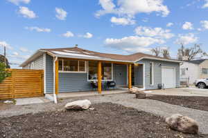 View of front facade with fence, driveway, a gate, a porch, and a garage